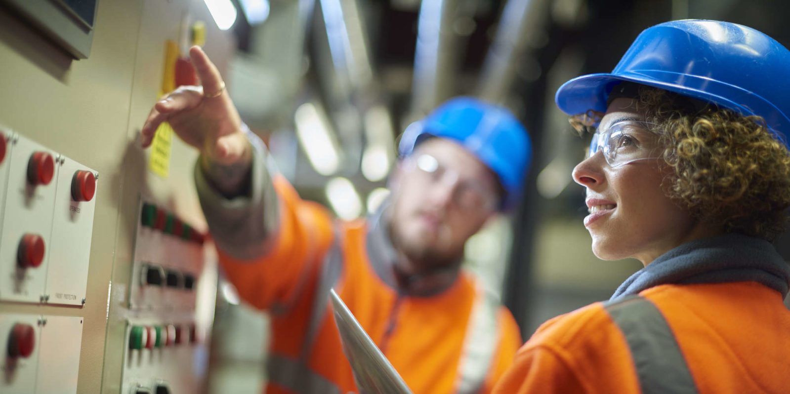 male and female skilled worker checking controls in manufacturing facility