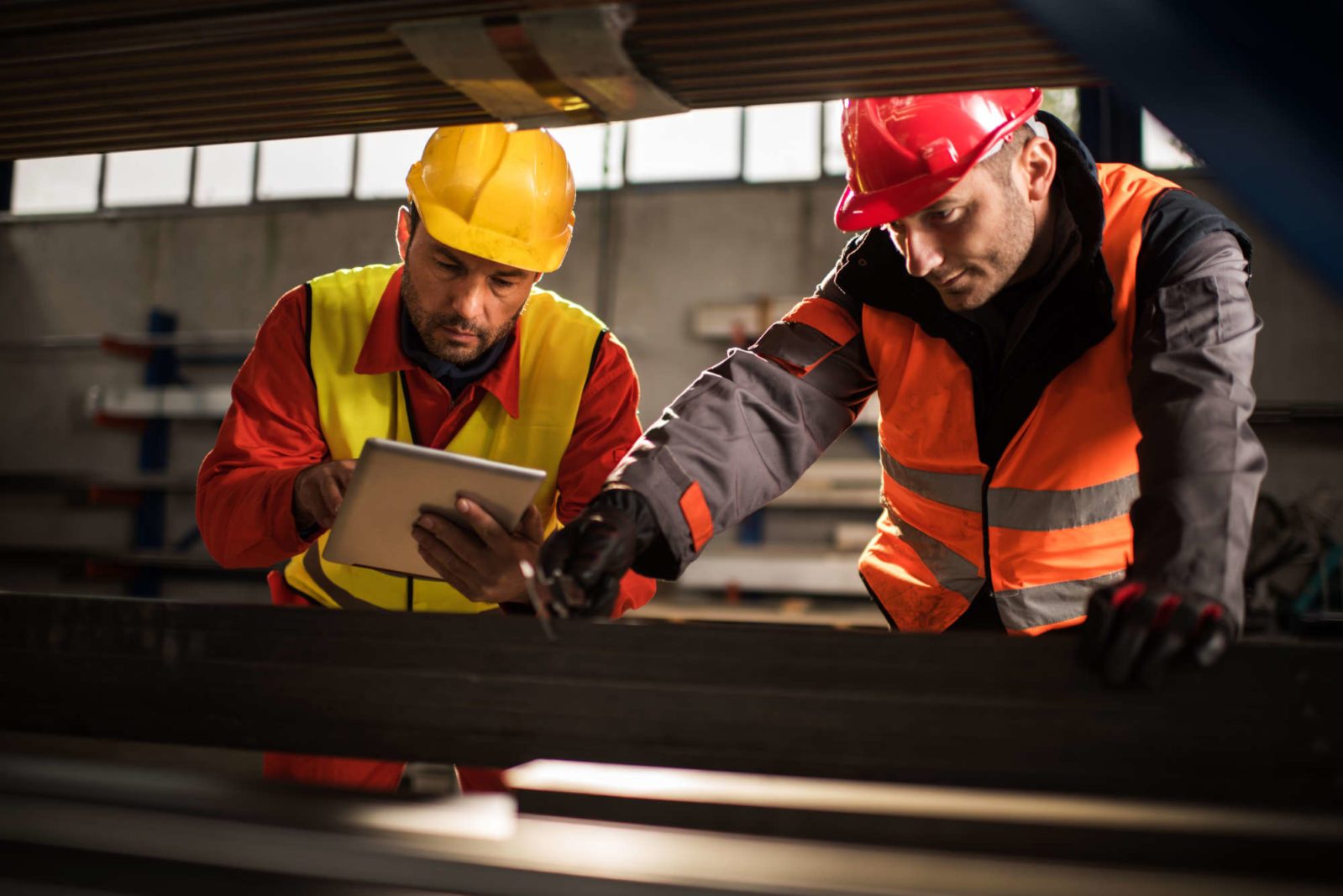 Manual workers cooperating while measuring metal in aluminum mill.