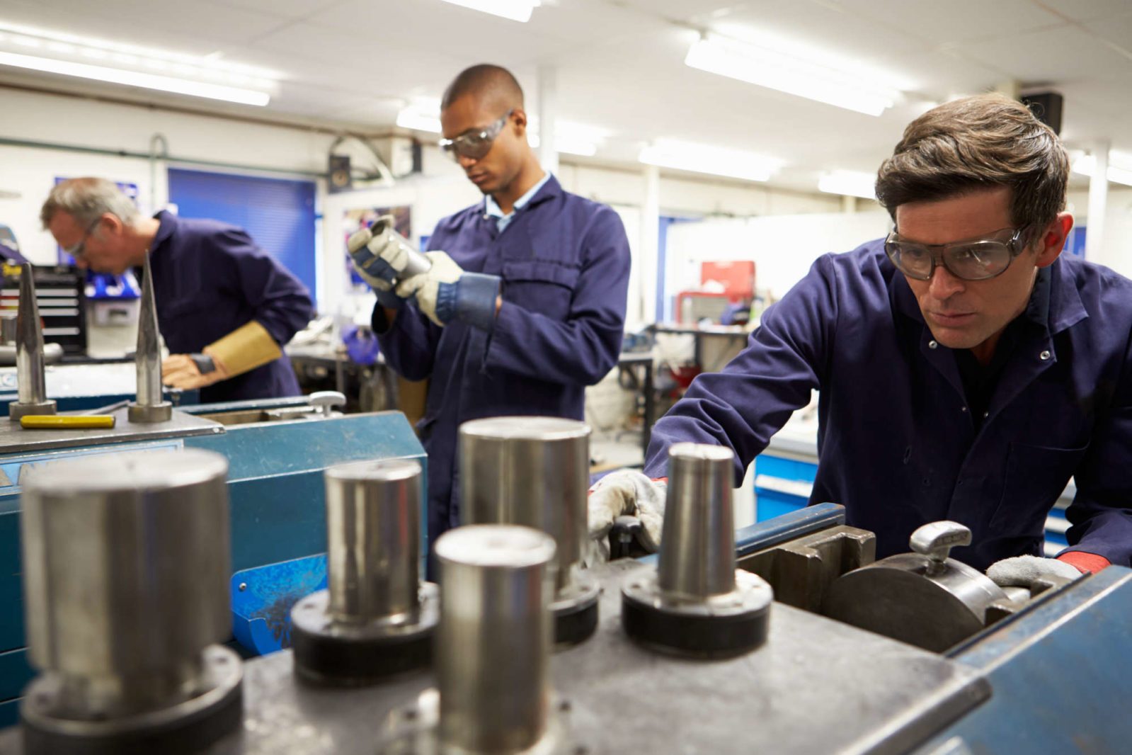 skilled workers at a manufacturing plant inspecting machinery